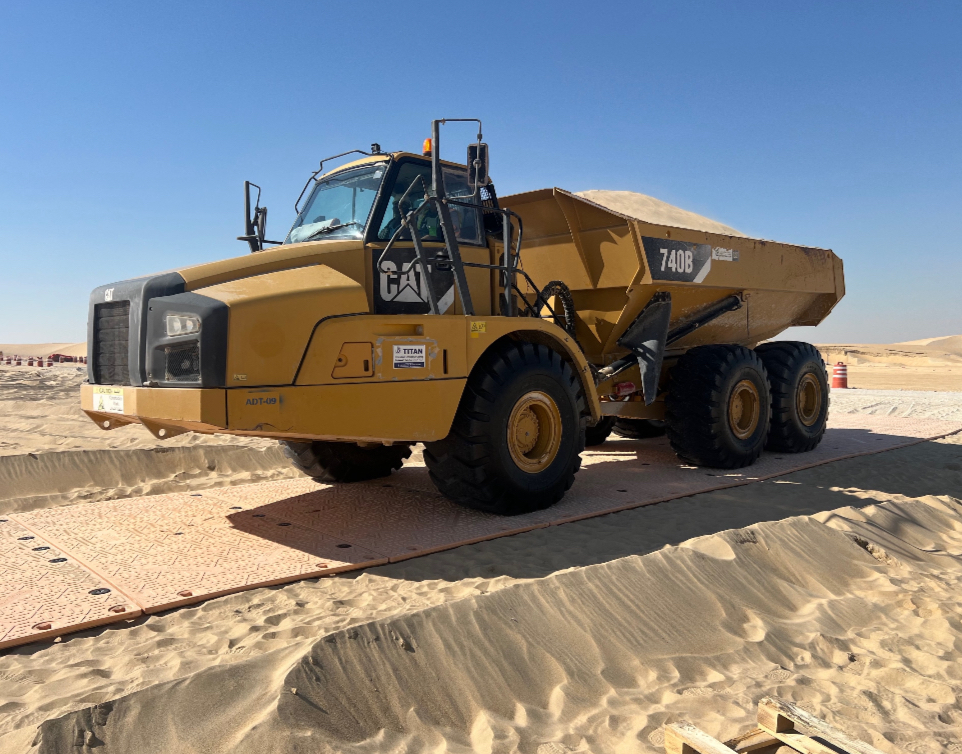 Articulated dump truck on temporary access matting in the desert